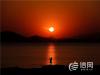 12月28日，一名市民正在拍摄胶州湾的夕阳。图片来源：信网 修相科 摄