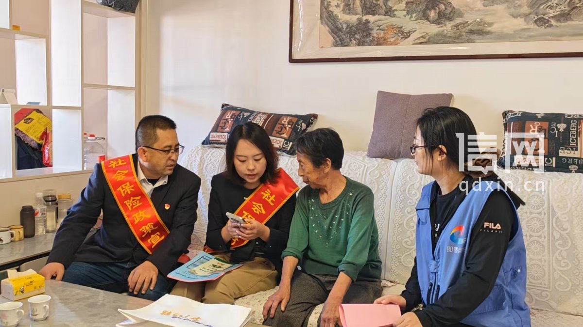 工作人员向老人演示操作过程。（来源：即墨区委宣传部）