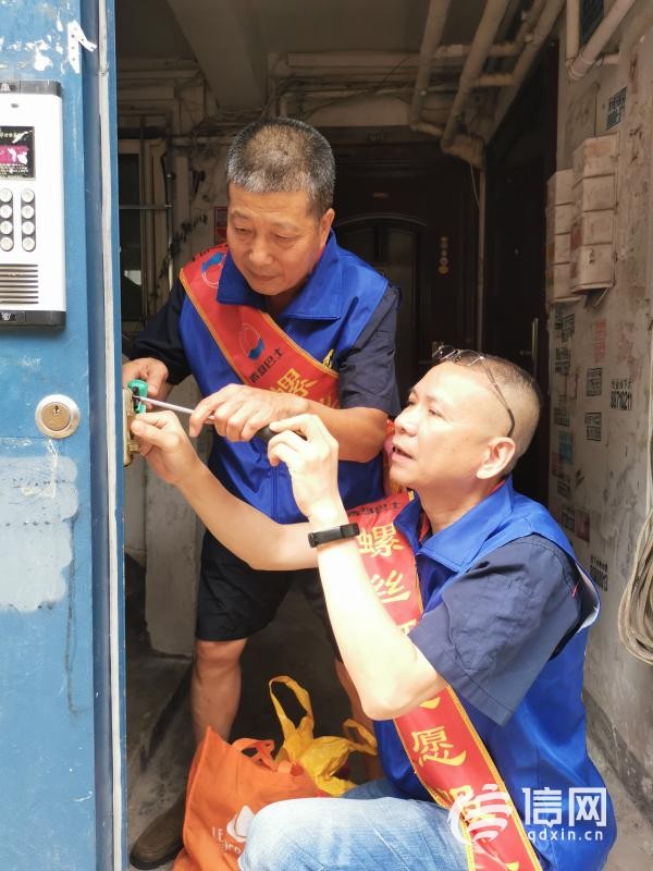 志愿者维修单元门。(来源：信网 首席记者 丛黎 摄)