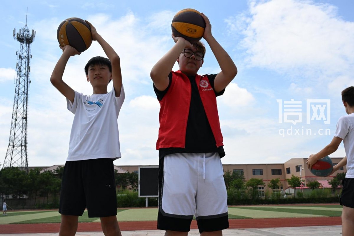 山东理工大学大学生志愿者指导孩子练习篮球投篮。（来源：即墨区委宣传部）