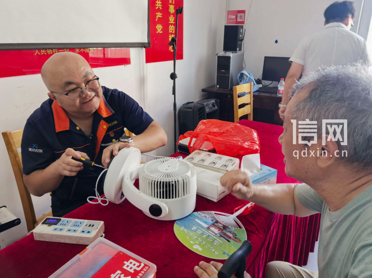志愿者胡冬冬为居民维修电风扇。(来源:信网)