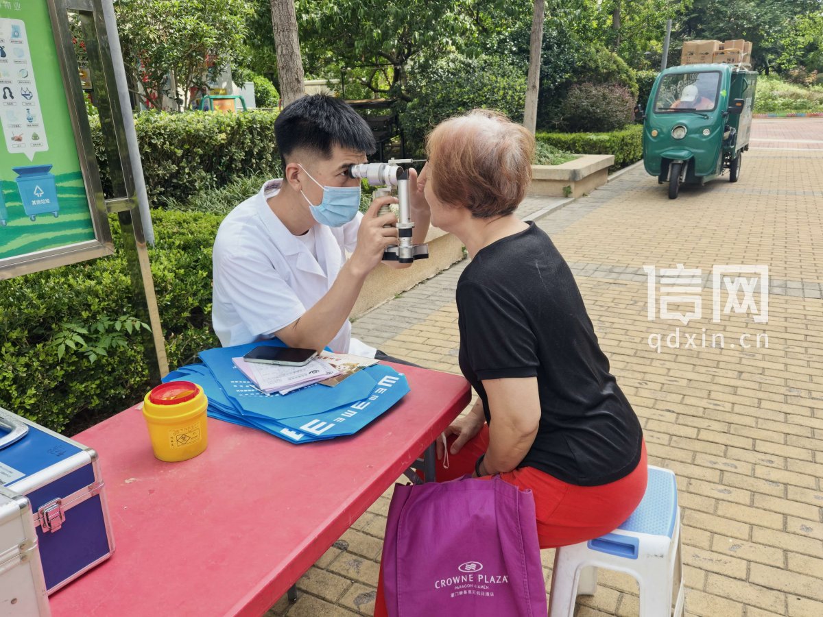 青岛眼科医院志愿者史先军为居民做白内障筛查。（来源：信网）