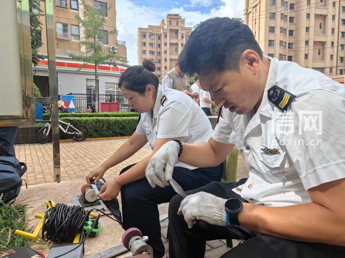 志愿者王正亮（前）、藏潇萌（后）为居民磨刀。（来源：信网）