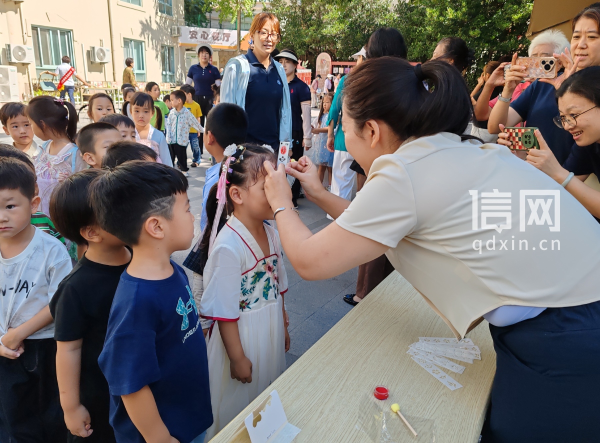 工作人员为孩子们绘制花钿眉心妆。（来源：珠海路街道）
